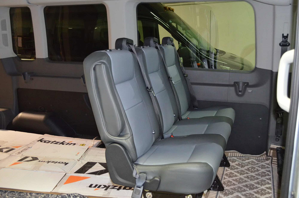 Modern van interior with gray seats and large windows.