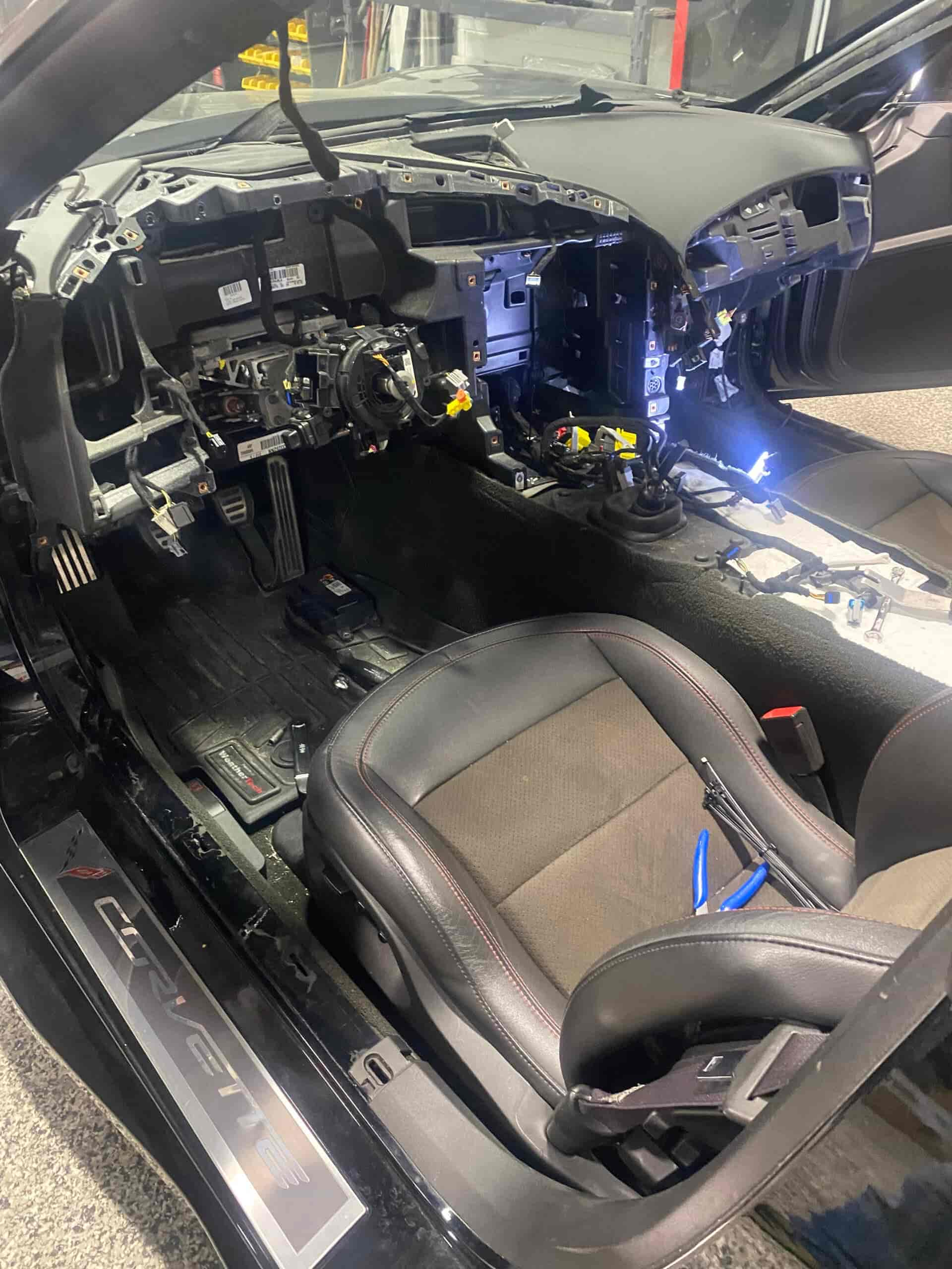 Interior of a race car undergoing restoration with exposed dashboard and wiring.