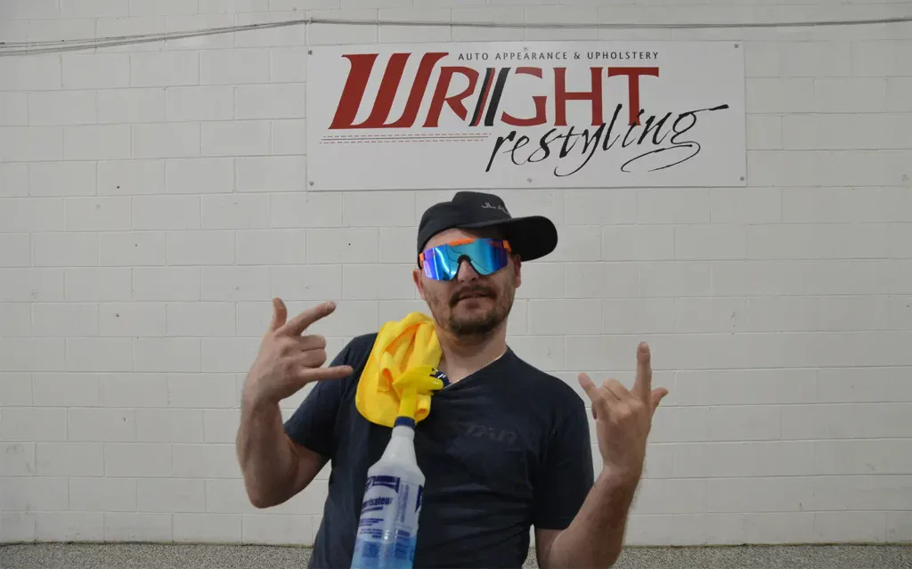 Auto detailing expert at Wright ReStyling with cleaning supplies and sunglasses.