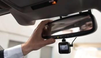Rearview mirror with dashcam capturing footage during driving.