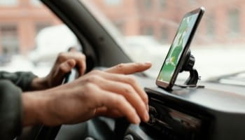 Modern car dashboard with hands using a smartphone mounted on the windshield.
