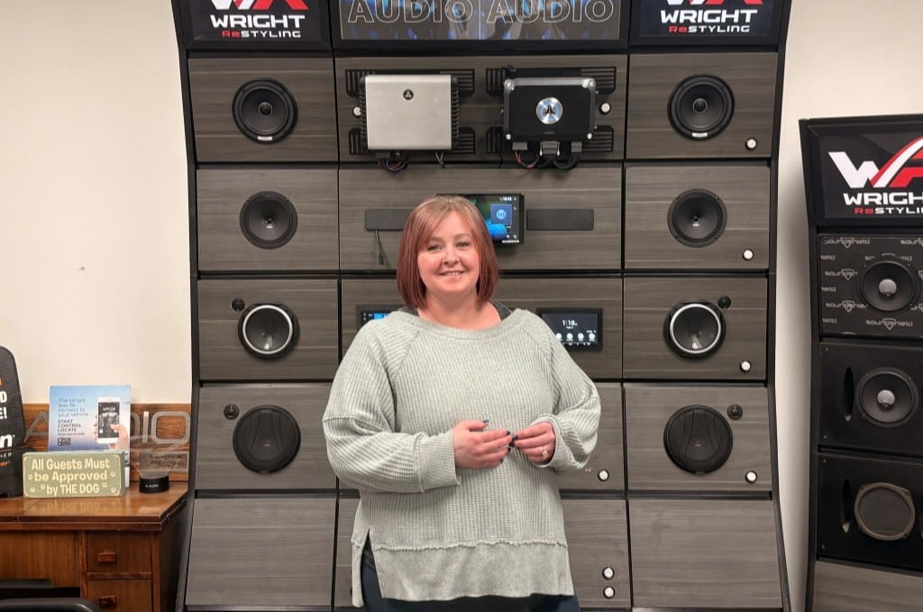 Woman smiling in front of audio equipment at Wright ReStyling.