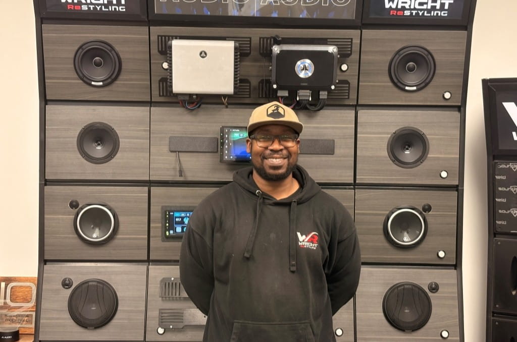 Smiling team member in front of audio equipment at Wright ReStyling.