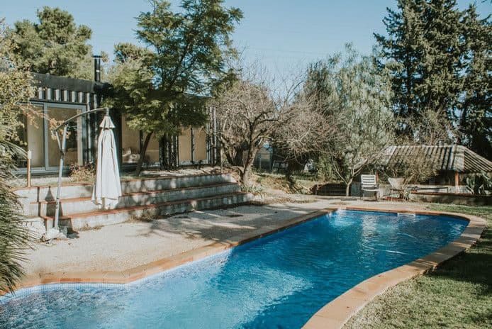 Jardín con piscina y árboles en casa rural.