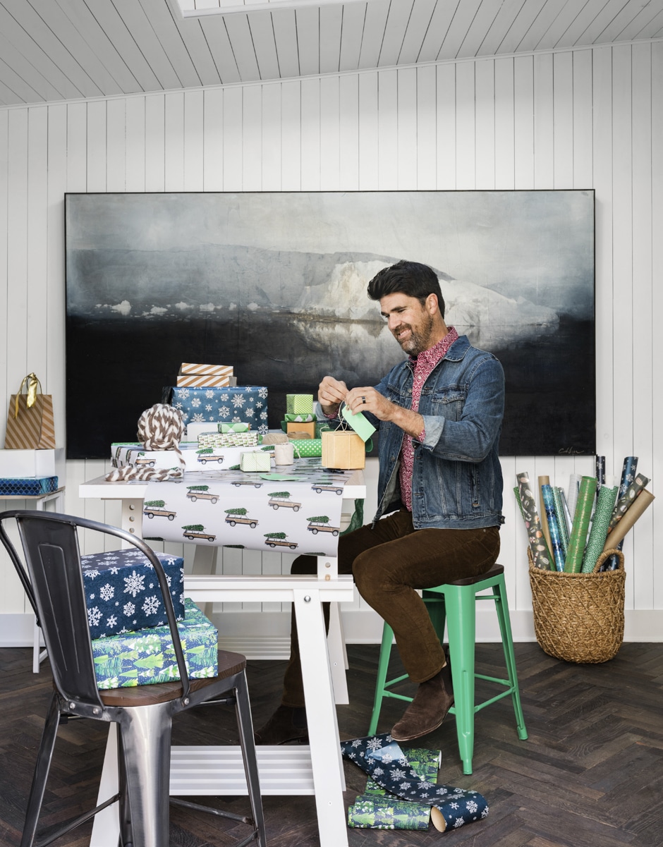 brian wrapping christmas presents in front of large painting