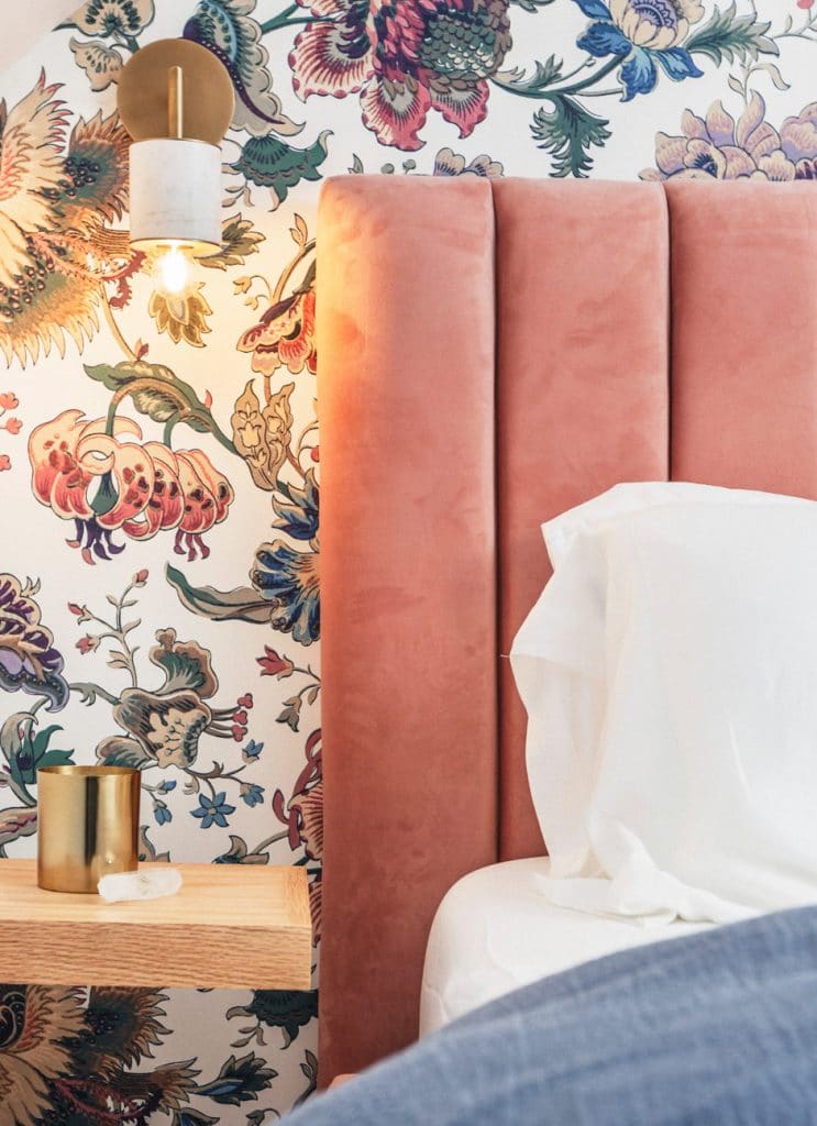 bedroom with patterned wallpaper and gold sconces