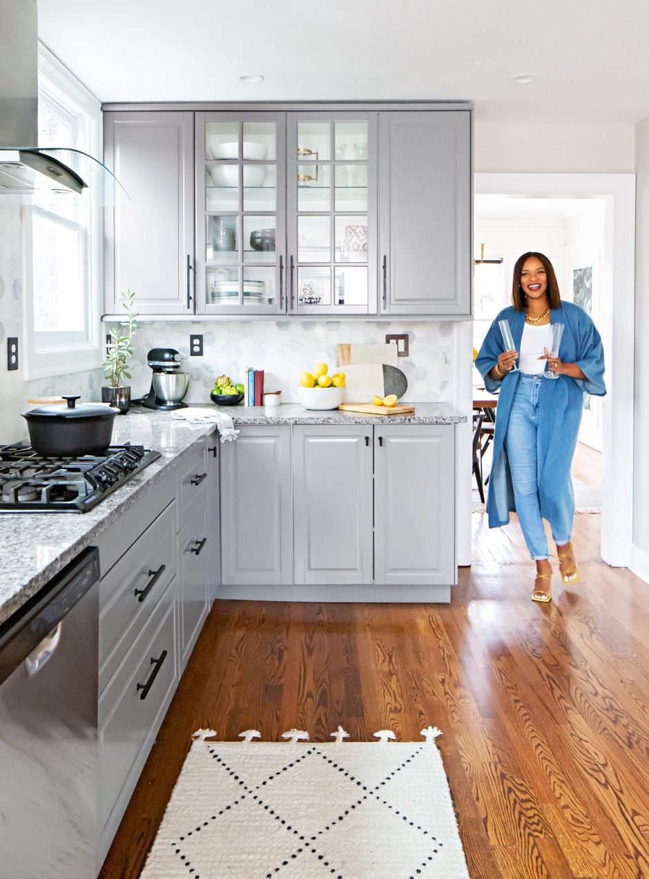 Candace walking into bright gray kitchen with hard wood floors