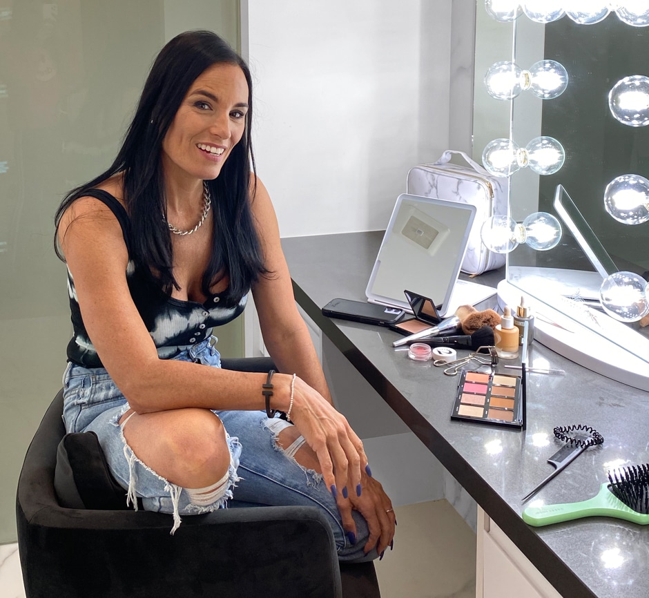 Heidi sitting at vanity putting on makeup