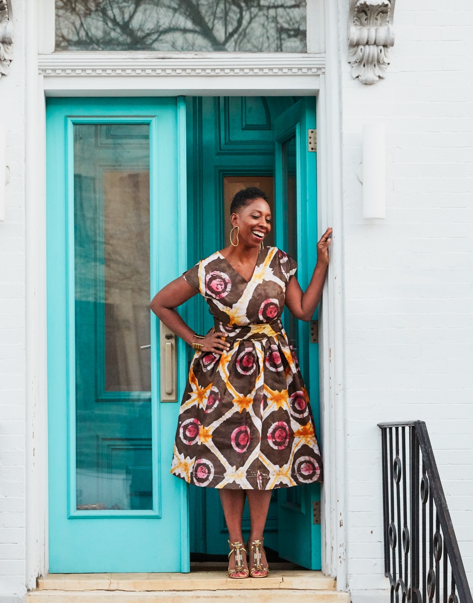 Malene standing in turquoise doorway outside of house