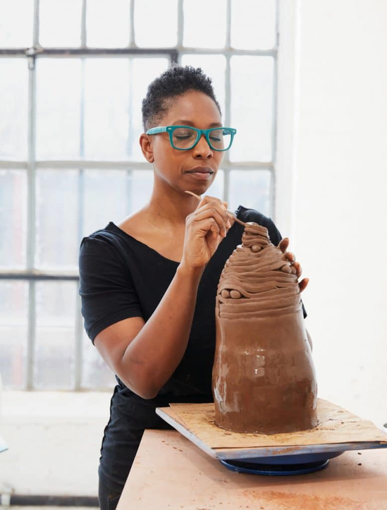 Malene sculpting clay with her eyes closed