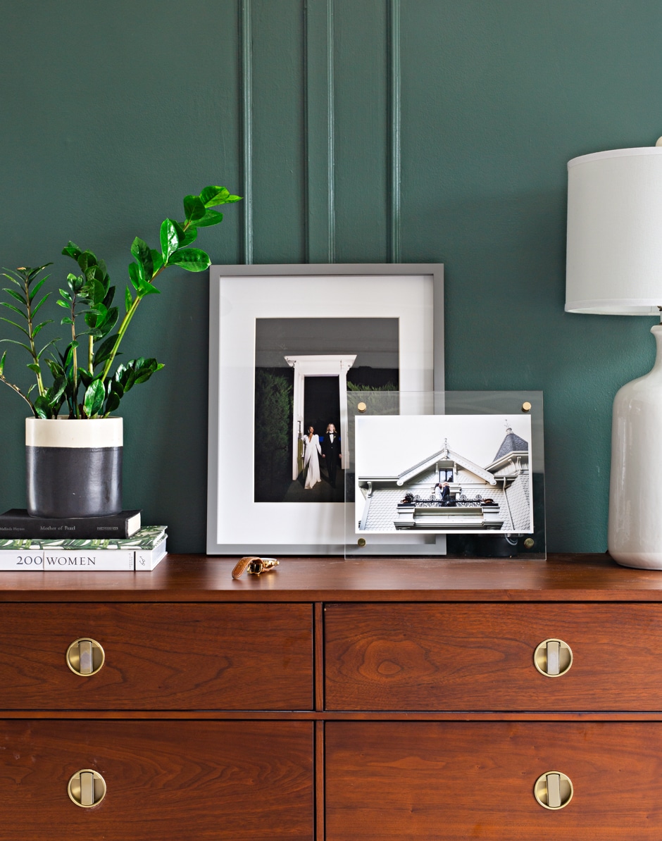 wooden midcentury dresser with plants and photos on top