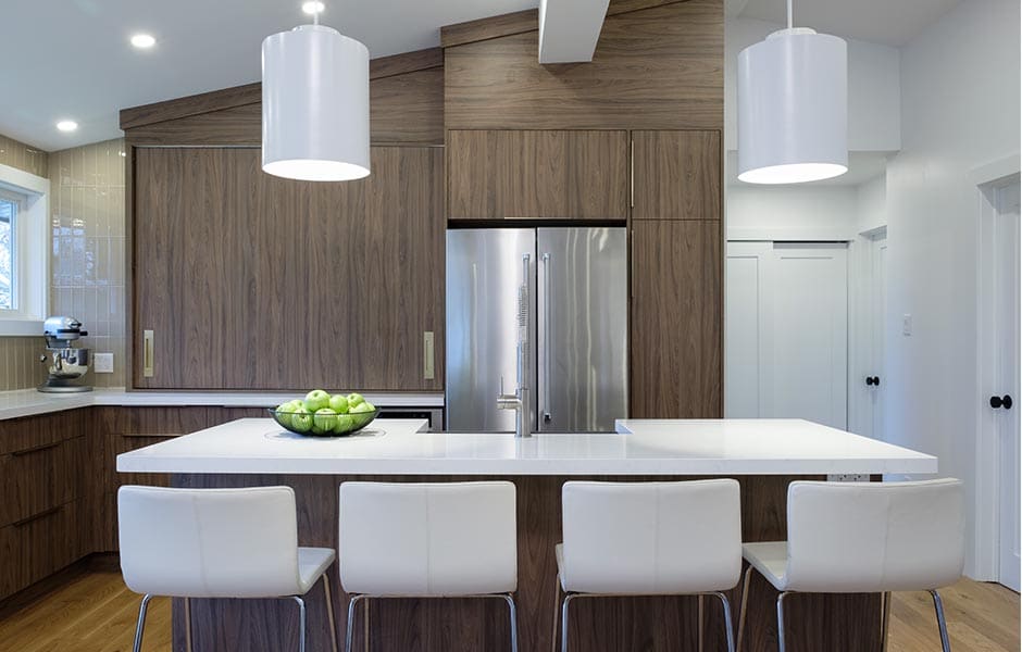 Modern kitchen with wood-grained cabinets, white island, and stainless steel fridge