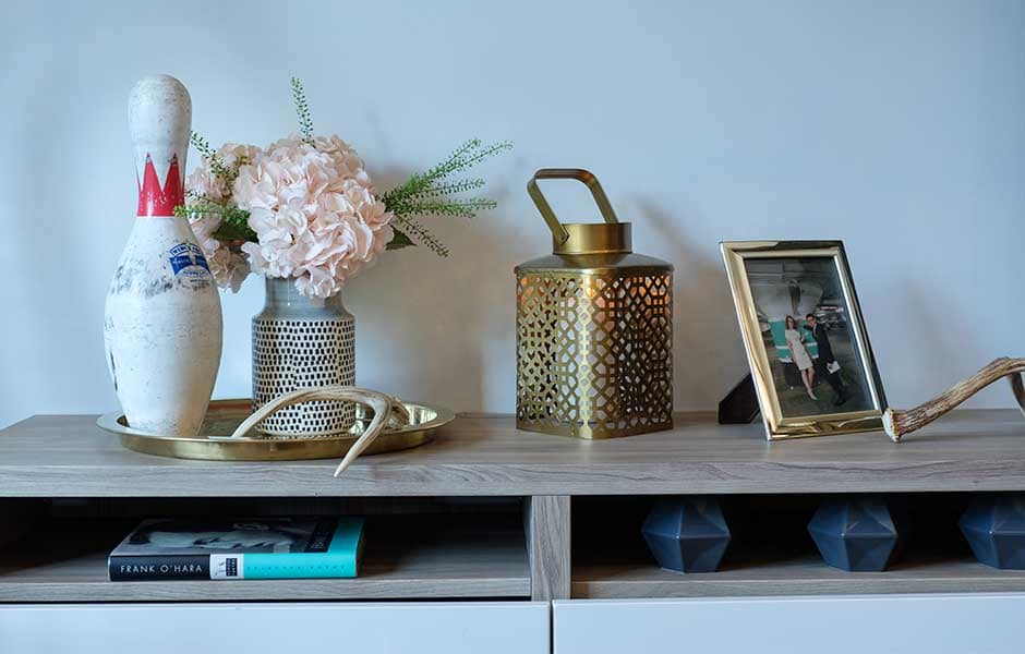 Console table decor: bowling pin, flowers, gold lantern, framed photo, and antlers