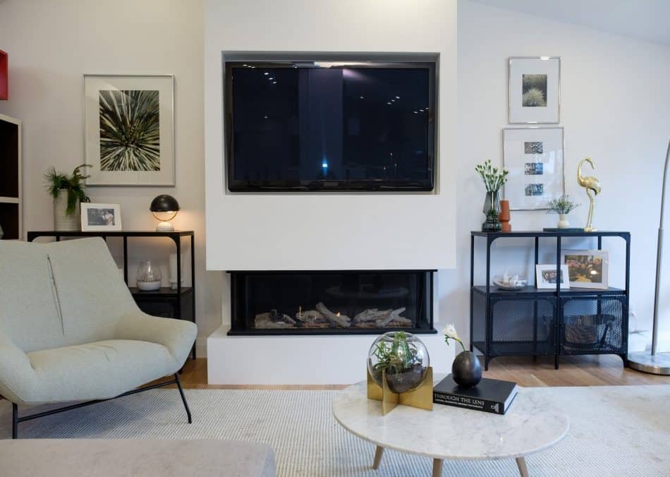 Fireplace with TV above, black shelves, and decorative accents