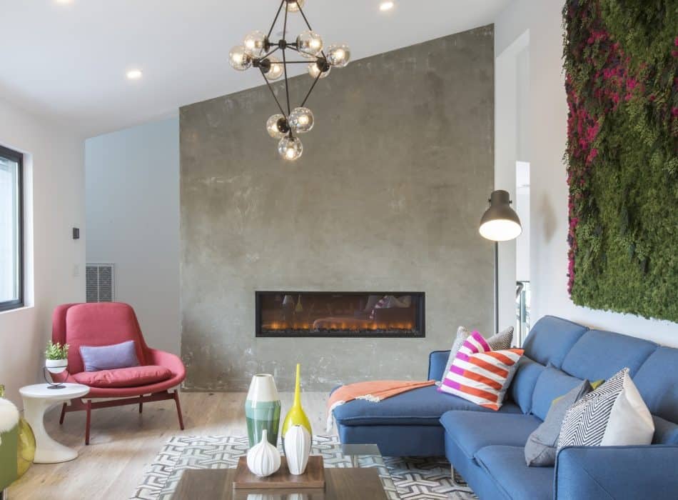 Living room with fireplace, blue sofa, red chair, and vertical garden
