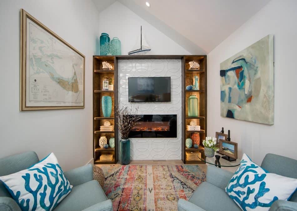 Living room with built-in shelves, wall-mounted TV, fireplace, and coastal-themed decor