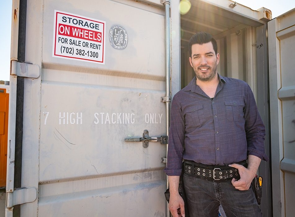 Jonathan Scott in a tool belt standing at the entrance of a shipping container labeled “Storage on Wheels.”