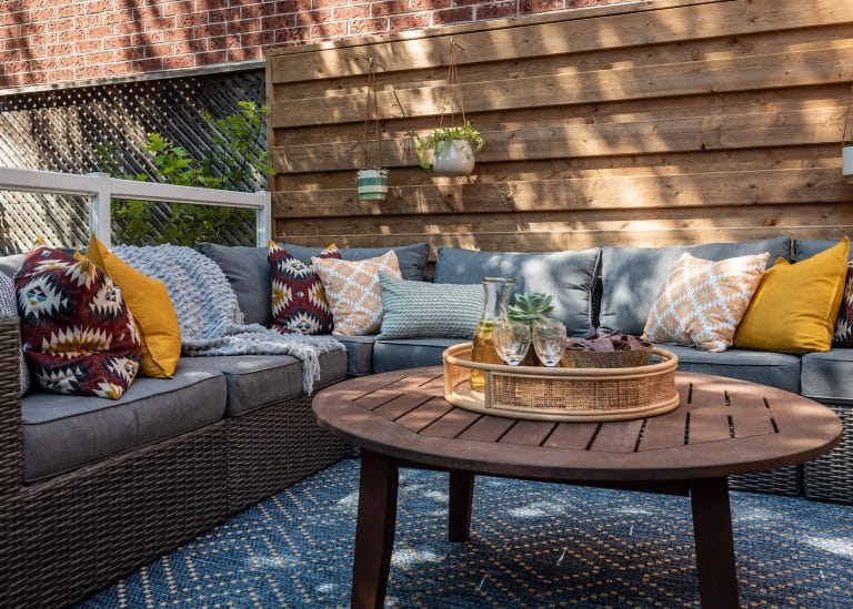 Outdoor patio with wicker seating, colorful pillows, and a wooden coffee table