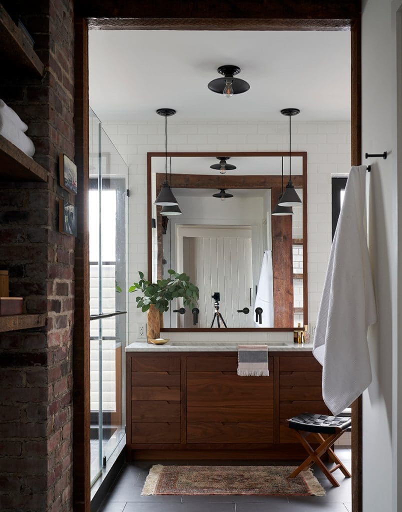 Stylish bathroom with wood vanity, large framed mirror, and black pendant lights