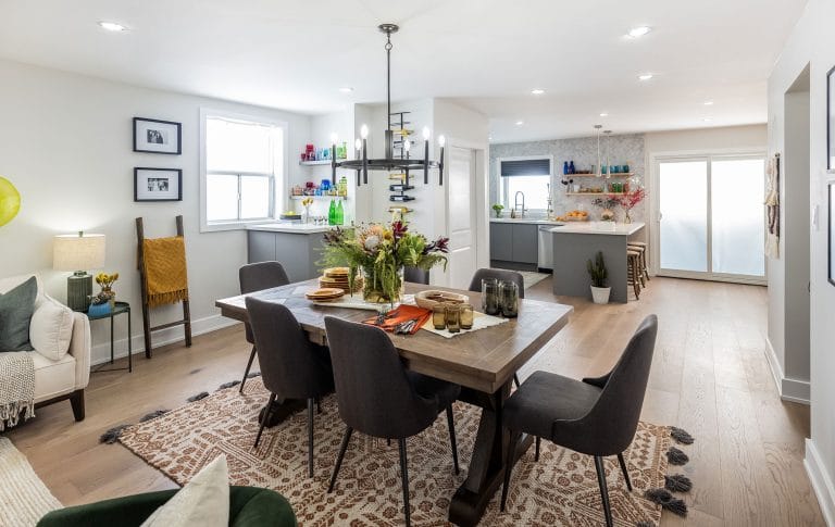 Open dining and kitchen area with a wooden table, black chairs, and vibrant decor accents