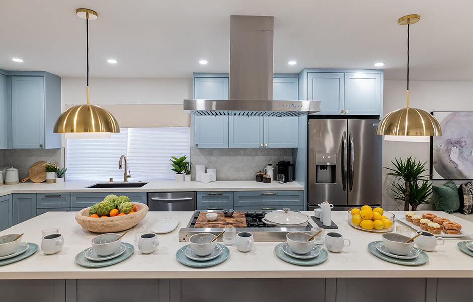 Modern kitchen with light blue cabinets, stainless steel appliances, and a large island set for breakfast