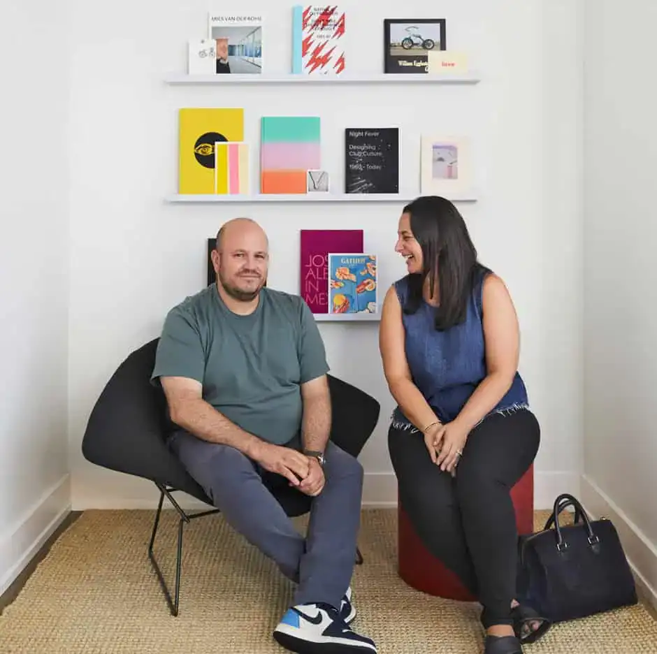 Everett and Valerie sitting in chairs with graphics and books on shelf behind