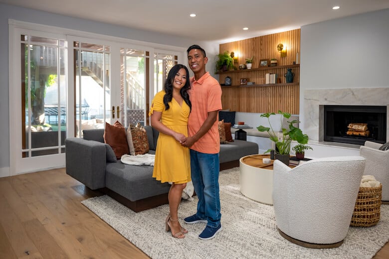 Couple standing in a modern living room with wood accents and neutral furniture