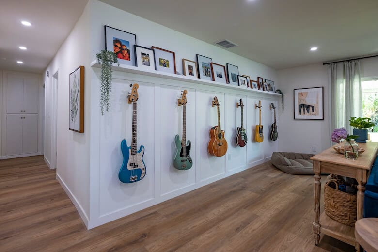 Room with guitars on white paneled wall and framed photos above