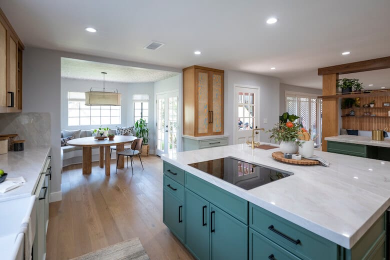 Open kitchen with green island, white countertops, and a breakfast nook with large windows