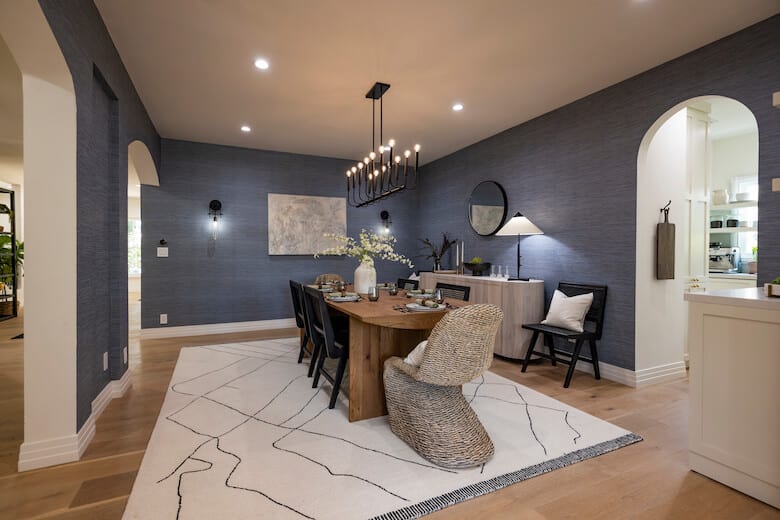 Dining room with navy walls, wood table, and chandelier