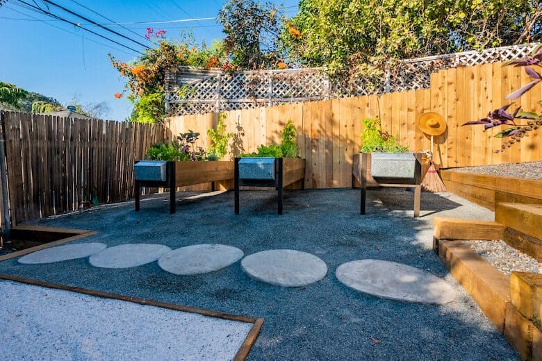 Backyard garden with raised planter boxes, wooden fencing, stepping stones, and wooden stairs