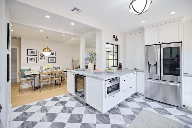 Kitchen with white cabinets marble countertops stainless steel refrigerator and checkered floor