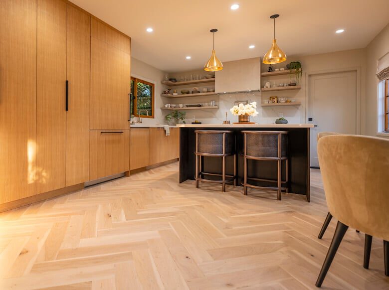 Warm kitchen with wood cabinets, black island, open shelves, and gold pendant lights