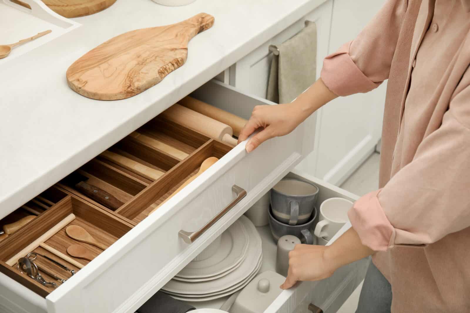 Hands opening drawers with utensils and dishes