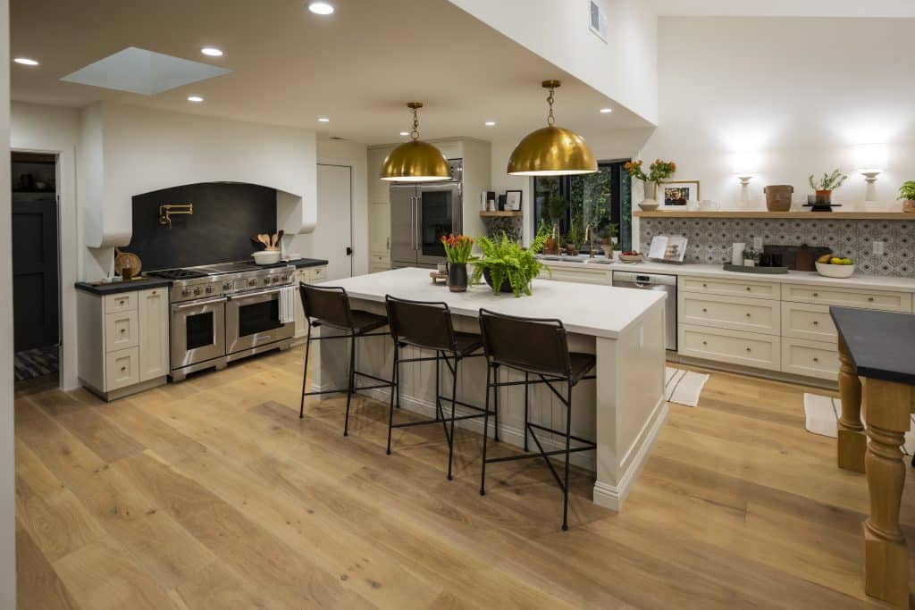 Spacious kitchen with large island, brass pendant lights, and light wood flooring