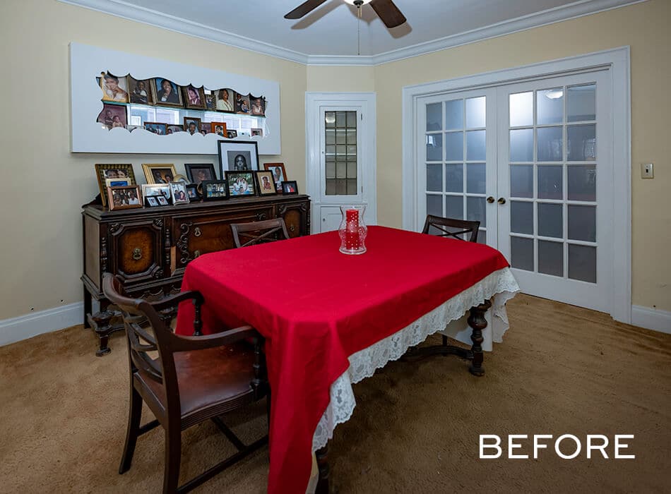 Traditional dining room with red tablecloth, framed family photos, and French doors