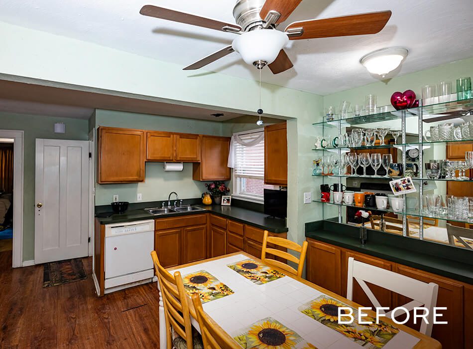 Dated kitchen with wood cabinets, sunflower-themed table setting, and mirrored glass shelving
