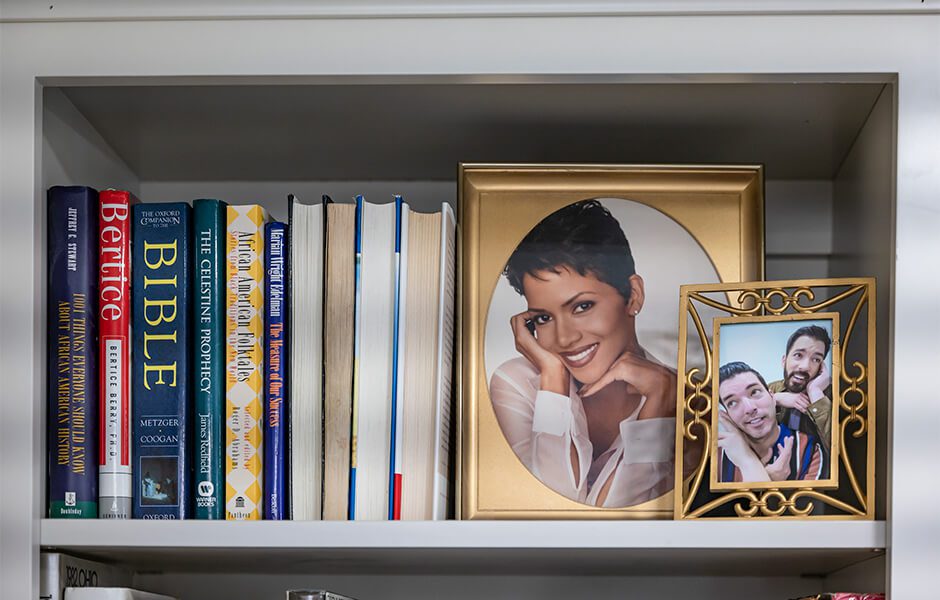 Bookshelf with hardcover books and two framed portrait photographs