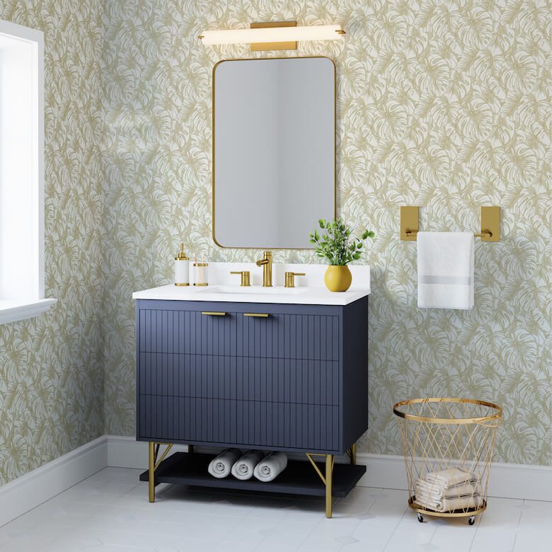 Elegant bathroom with navy vanity, gold fixtures, and patterned wallpaper