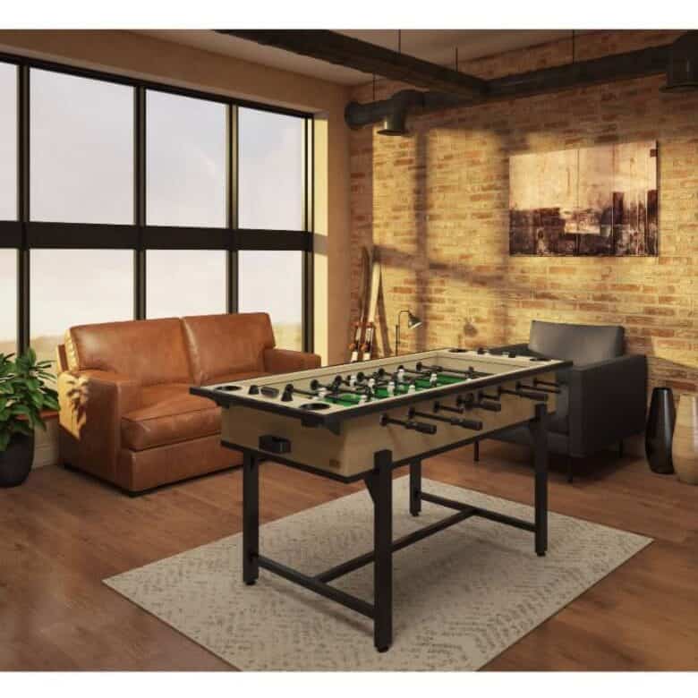 Industrial-style game room with brick walls, leather sofa, foosball table, and large windows