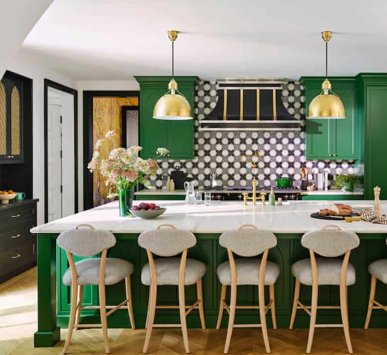 Kitchen with green cabinets, gold lights, and white island