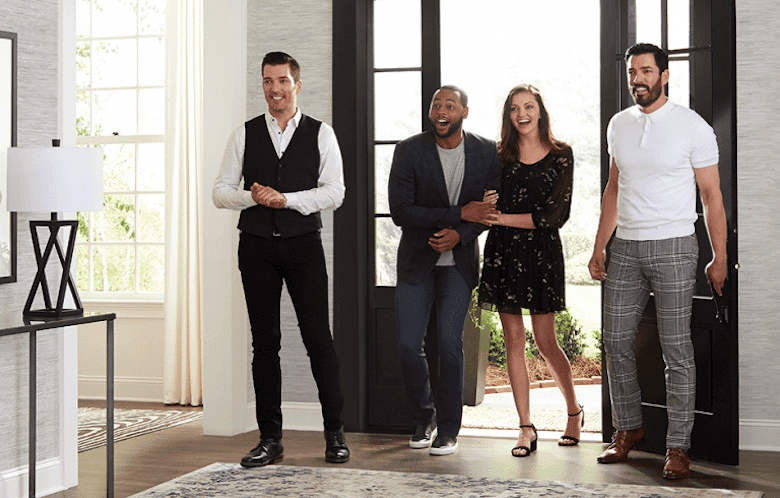 Four people standing in a bright entryway, smiling and reacting with excitement