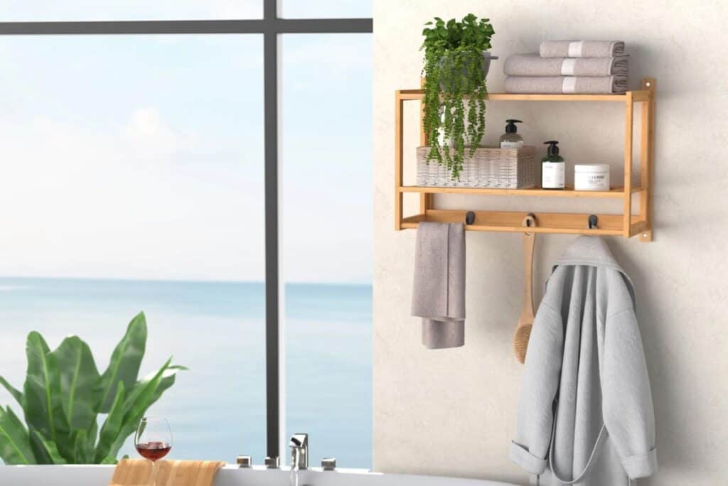Bathroom with a wooden wall shelf, towels, plants, and a robe, overlooking an ocean view