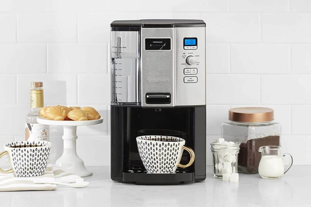 Cuisinart coffee maker with mug, sugar, milk, cookies, and coffee jar on counter