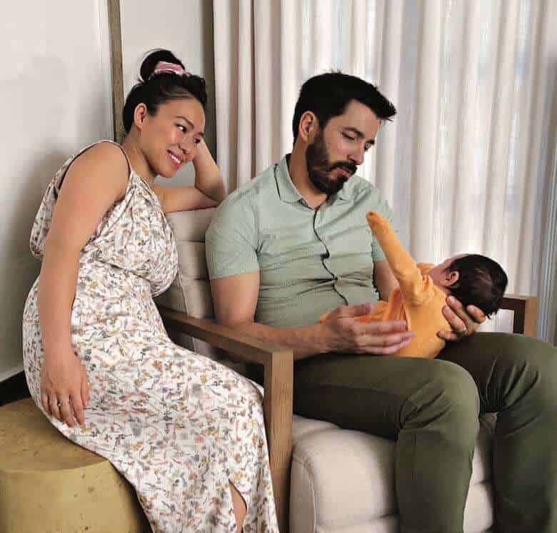 Drew holding baby Parker in orange outfit while Linda in floral dress smiles beside them