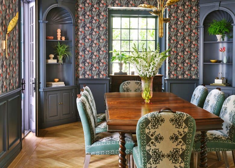 Traditional dining room with floral wallpaper, wooden table, and patterned upholstered chairs