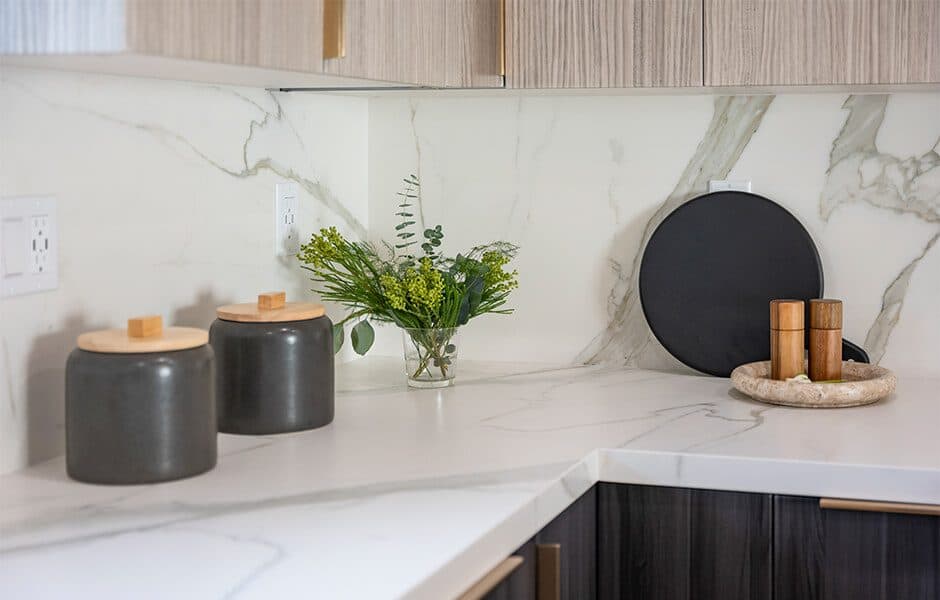 Modern kitchen corner with marble backsplash, black canisters, fresh greenery, and wooden spice containers