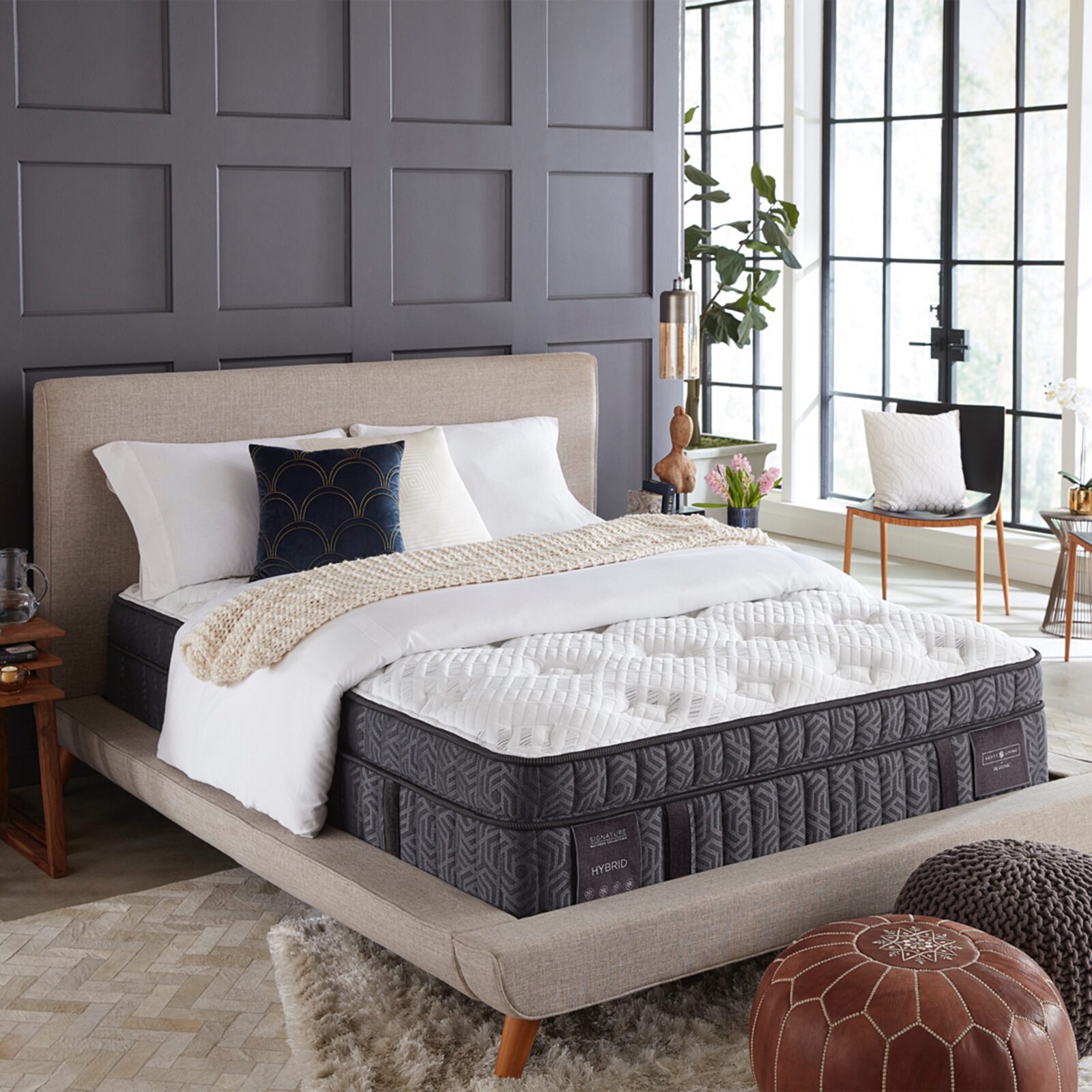 Stylish bedroom with a modern upholstered bed, hybrid mattress, dark accent wall, and large grid windows