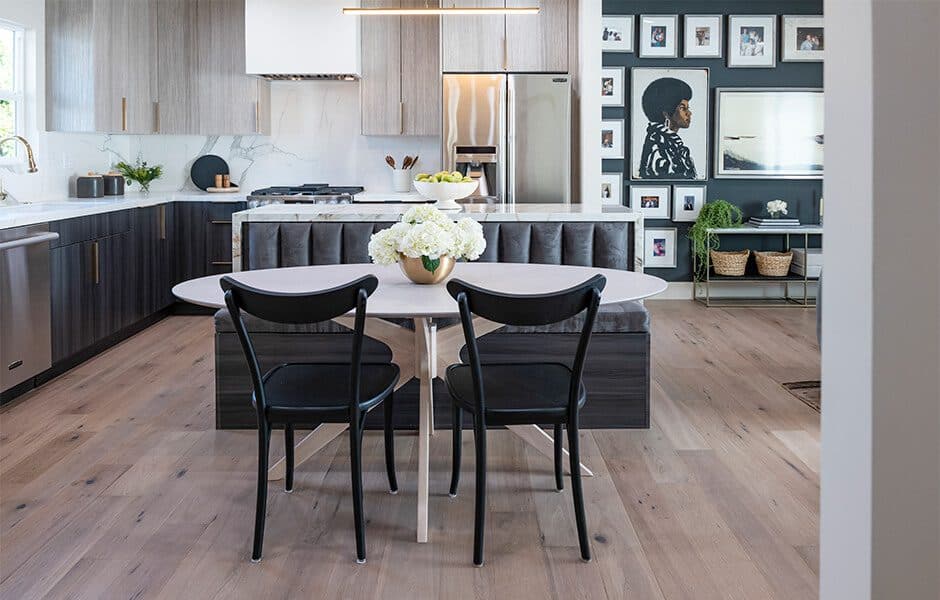 Modern kitchen with dark cabinets, marble backsplash, oval dining table, and black chairs