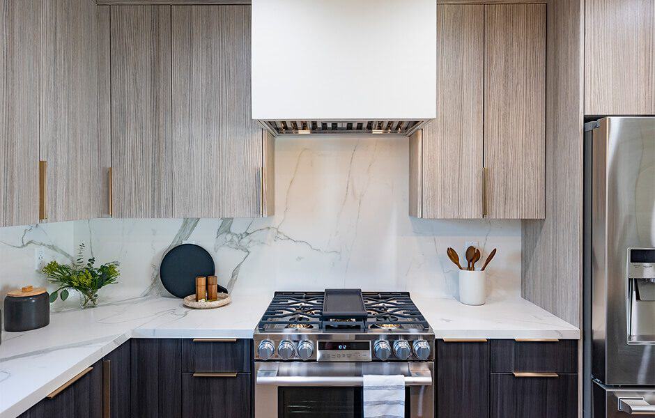 Contemporary kitchen with a stainless steel stove, marble backsplash, wood cabinets, and minimal decor